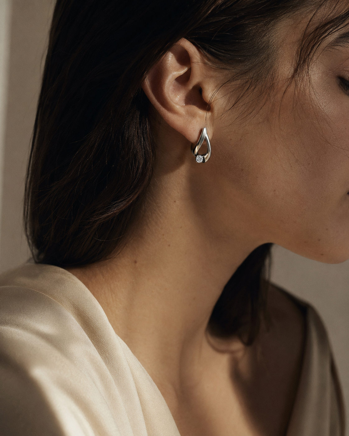 Perfil de una mujer con un arete escultórico de metal blanco y diamante